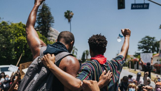 Picture of two men holding each other in solidarity at a Black Lives Matter protest