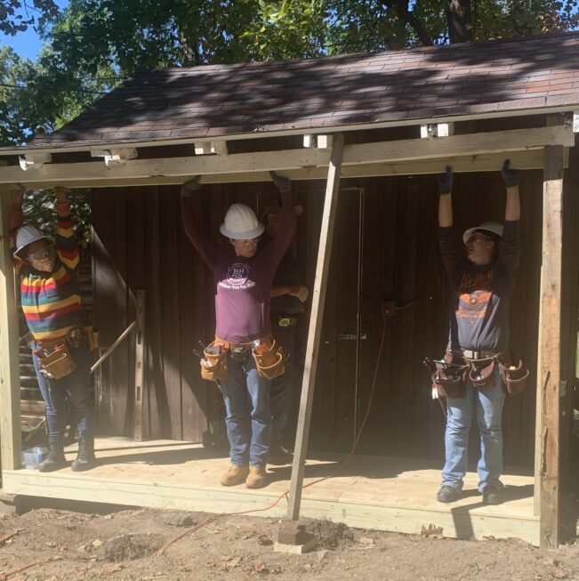 Lifting beams, raising confidence. SUFW students apply their carpentry skills while giving back to their community.SUFW students are pictured here setting a beam on a local 4-H cabin.